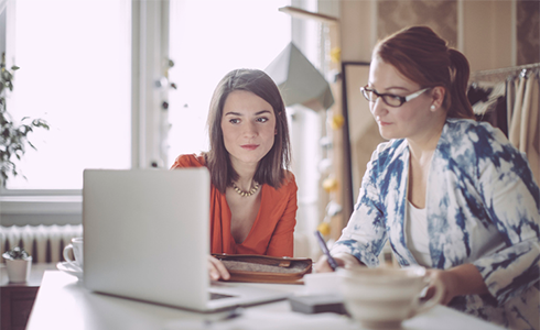 two female employees focused on a laptop screen